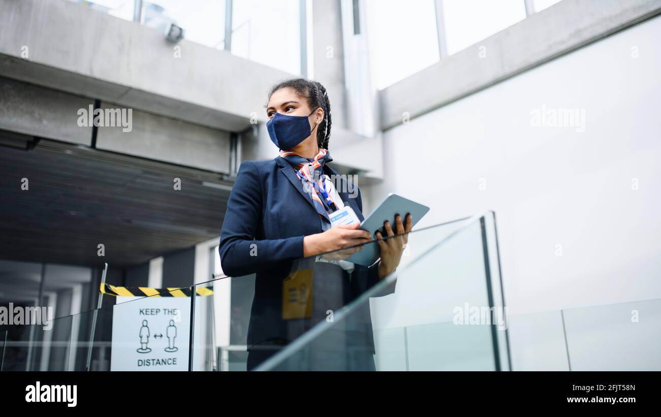 Giovane hostess aria in aeroporto lounge, coronavirus, viaggi e nuovo normale. Foto Stock