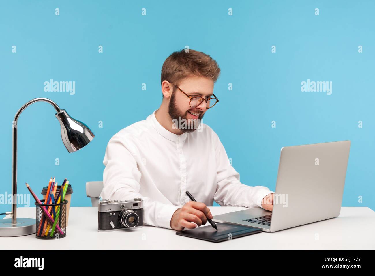 Uomo sorridente bearded illustrazione designer pittura con stilo su tavoletta grafica, lavorando su contenuti multimediali, ritocco schizzi. Studio interno sh Foto Stock