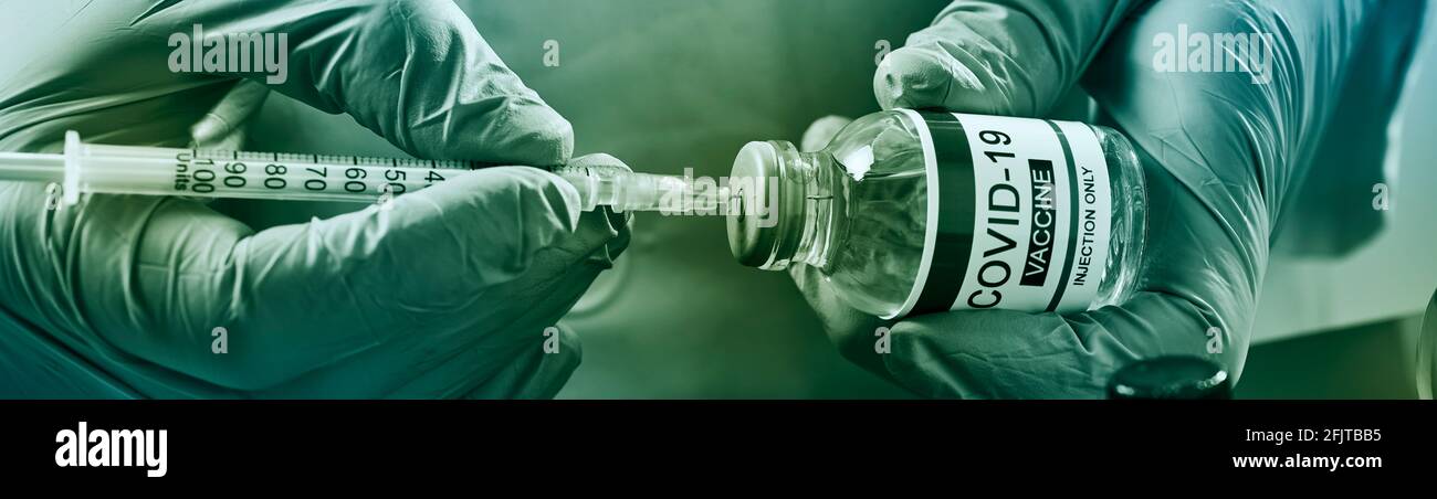 chiusura di un operatore sanitario o di laboratorio, indossando guanti chirurgici, riempiendo una siringa da un flaconcino simulato di un vaccino covid-19, in una panoramica f Foto Stock