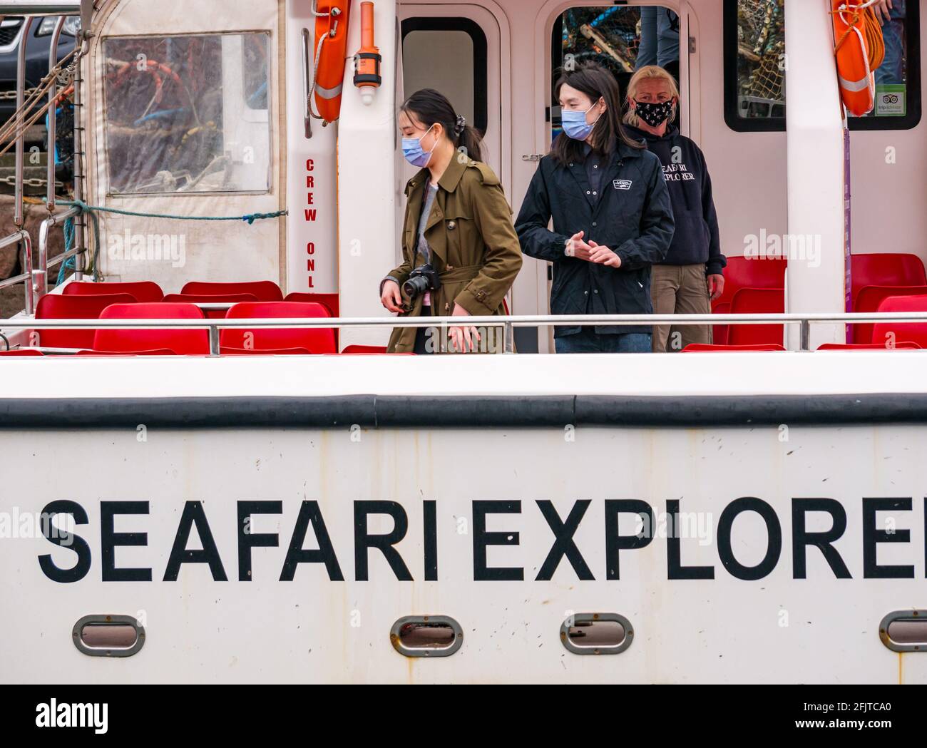 North Berwick, East Lothian, Scozia, Regno Unito, 26 aprile. Riaprire le aziende: Con le restrizioni di blocco attenuate oggi, lo Scottish Seabird Center prima gita turistica in barca da crociera si svolge dall'anno scorso. Nella foto: I passeggeri saliscono a bordo del catamarano SEAFARI Explorer indossando maschere facciali Foto Stock