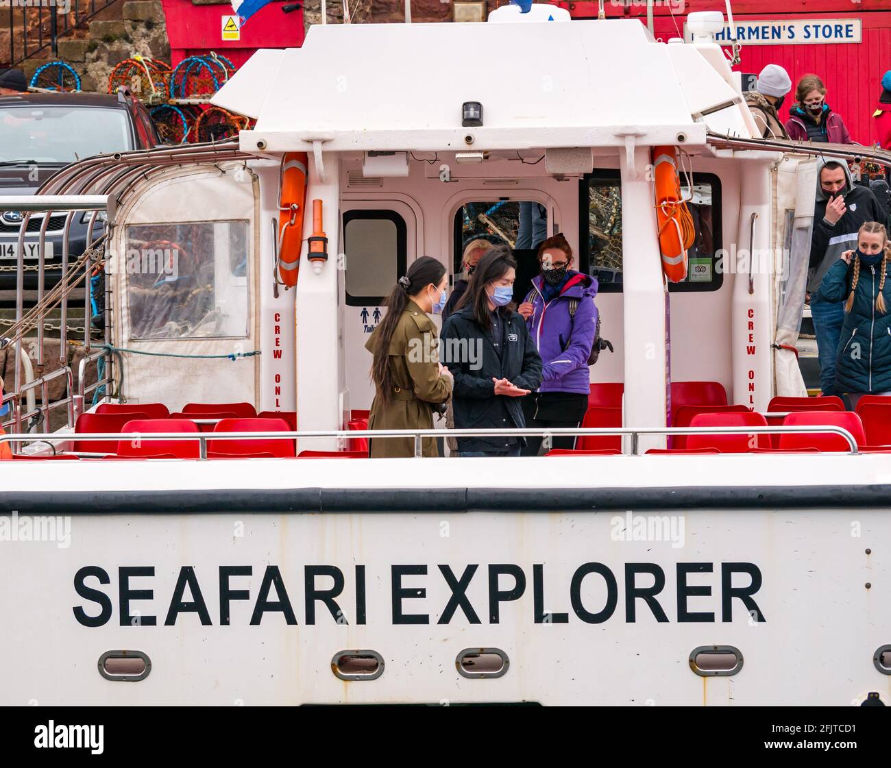 North Berwick, East Lothian, Scozia, Regno Unito, 26 aprile. Riaprire le aziende: Con le restrizioni di blocco attenuate oggi, lo Scottish Seabird Center prima gita turistica in barca da crociera si svolge dall'anno scorso. Nella foto: I passeggeri saliscono a bordo del catamarano SEAFARI Explorer indossando maschere facciali Foto Stock