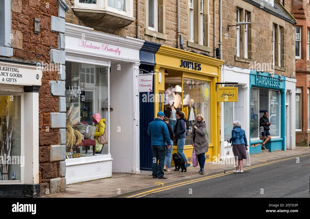 North Berwick, East Lothian, Scozia, Regno Unito, 26 aprile. Le aziende riaprono: Con le restrizioni di blocco attenuate oggi, i negozi sono aperti. Nella foto: Le persone che indossano maschere facciali accodano fuori da un negozio Joules in High Street. Foto Stock