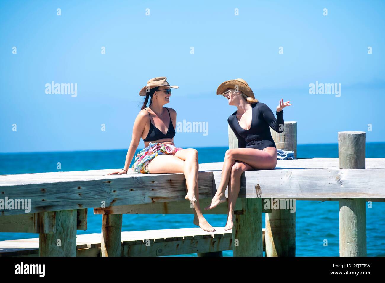 Due donne che si rilassano su un molo nei Caraibi Foto Stock