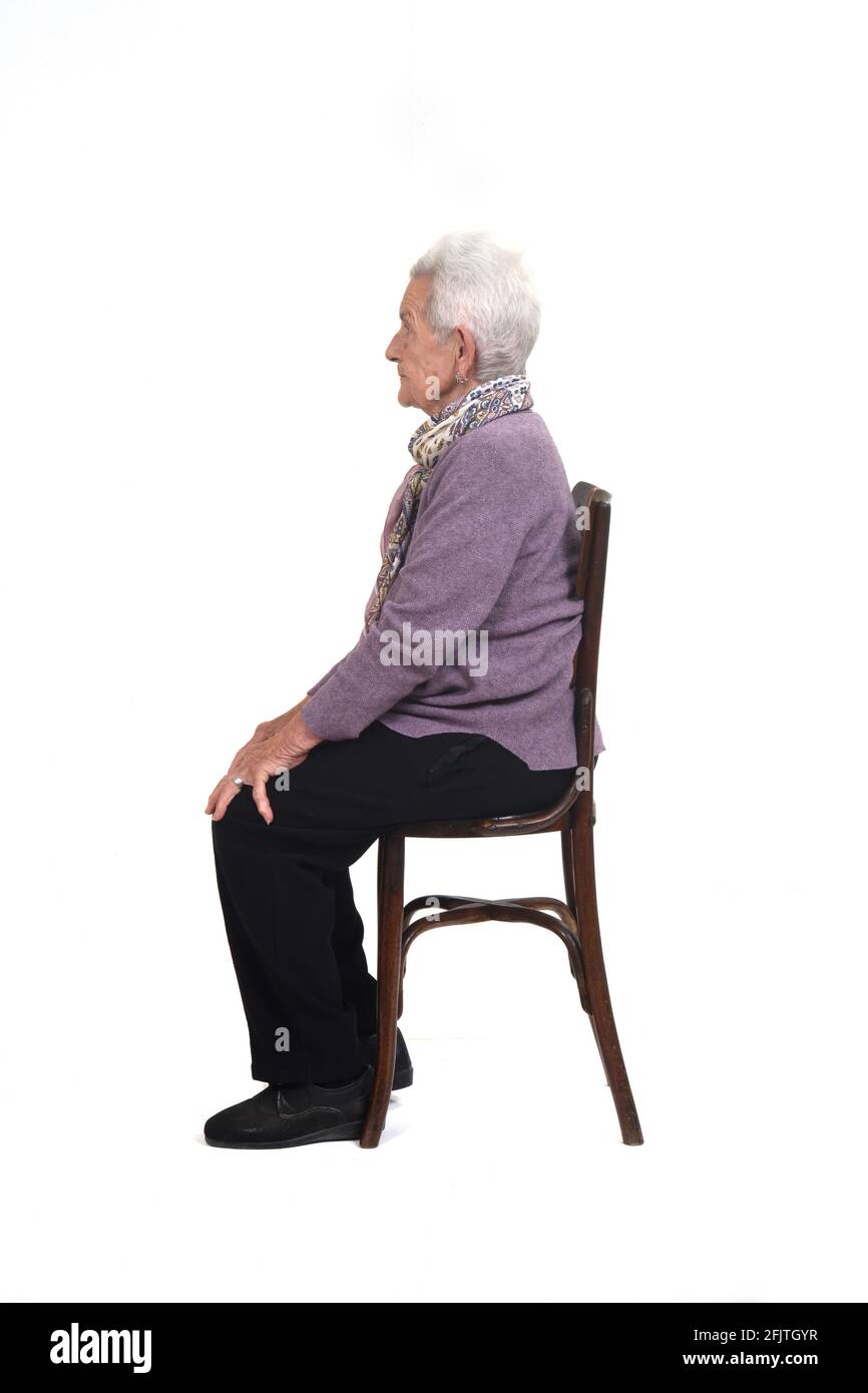 vista laterale di una donna senir seduta su una sedia sfondo bianco Foto Stock