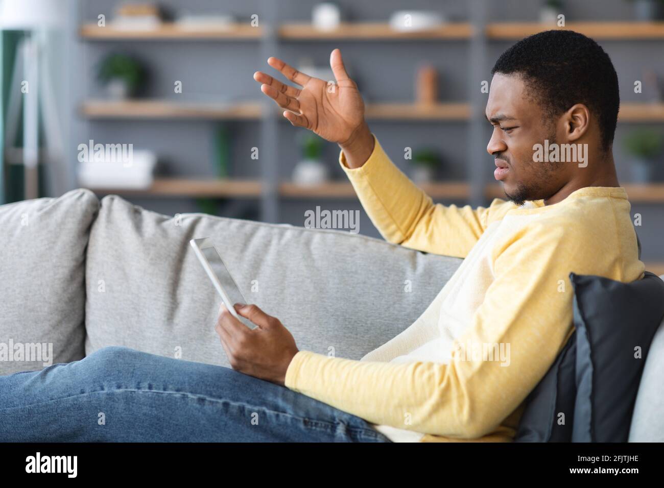 Arrabbiato uomo afroamericano che tiene un tablet digitale Foto Stock