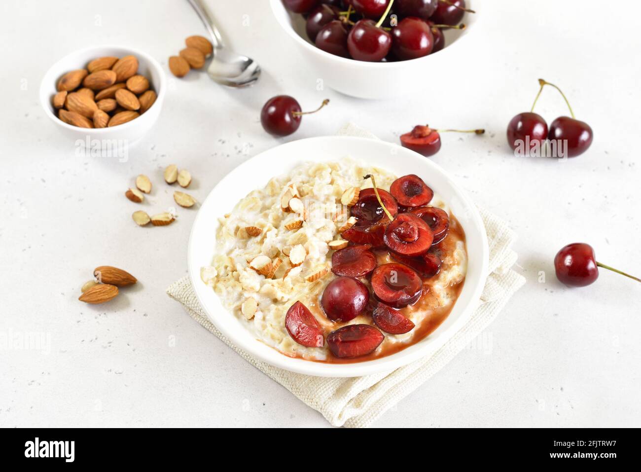 Porridge con fette di ciliegia e noci nel recipiente Foto Stock