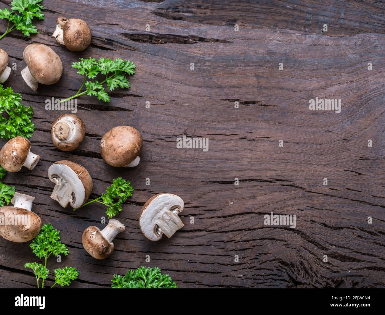 Funghi comuni di colore marrone su tavola di legno con erbe. Vista dall'alto. Foto Stock