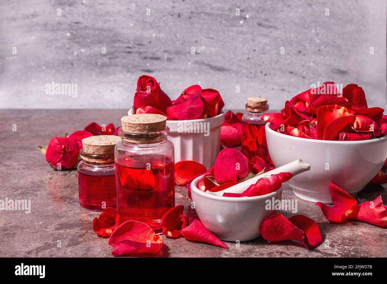 Rosewater con petali di rosa. Fare essenza di rosa organica per cucinare Kerala India. Aromaterapia, relax spa, concetto cosmetico. Luce moderna, Foto Stock