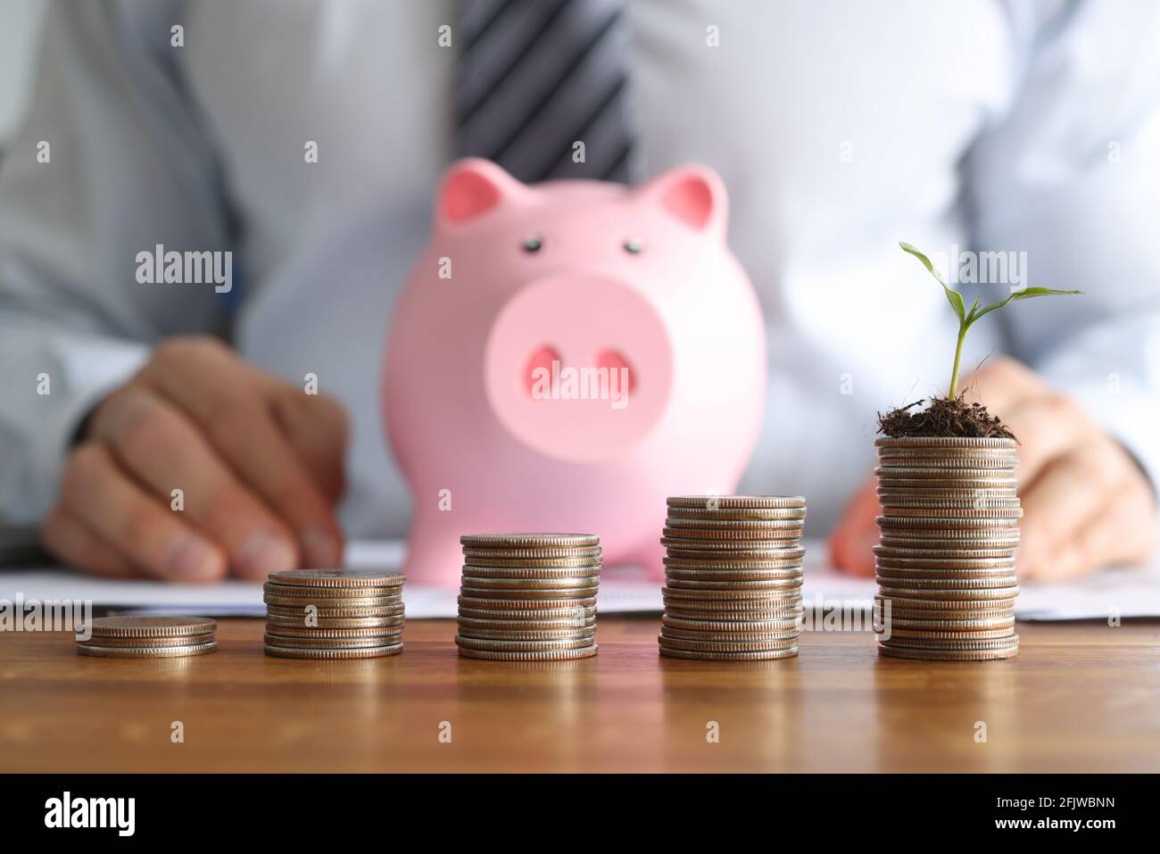 Davanti a uomini d'affari sono cilindri di monete e rosa porcellino banca Foto Stock