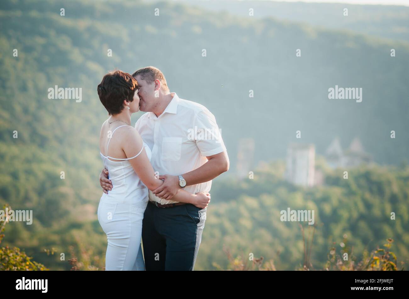 Abbraccio e bacio degli sposi novelli sullo sfondo della foresta Foto Stock
