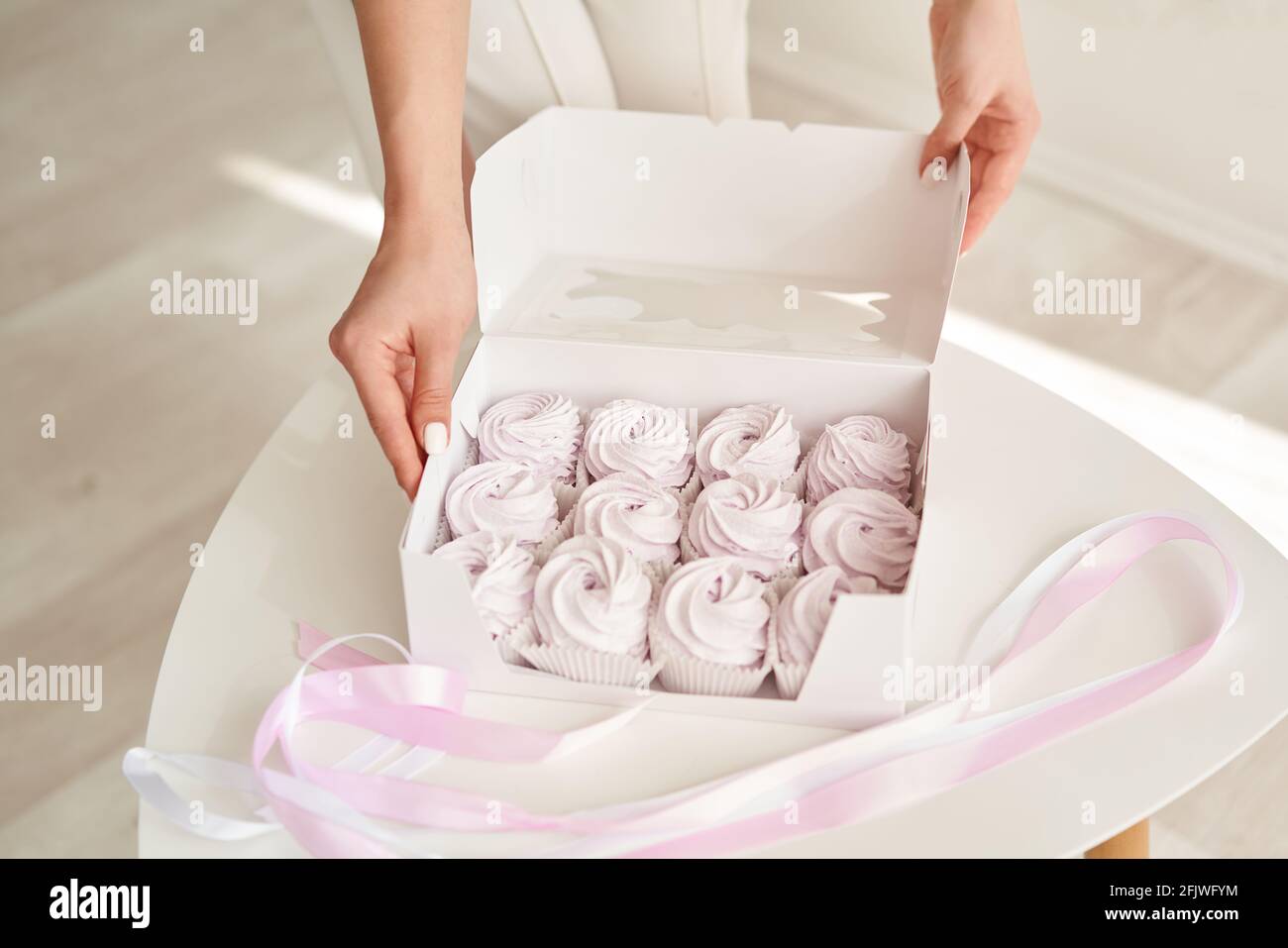 Chef pasticceria ragazza che tiene marshmallows rosa in confezione regalo Foto Stock