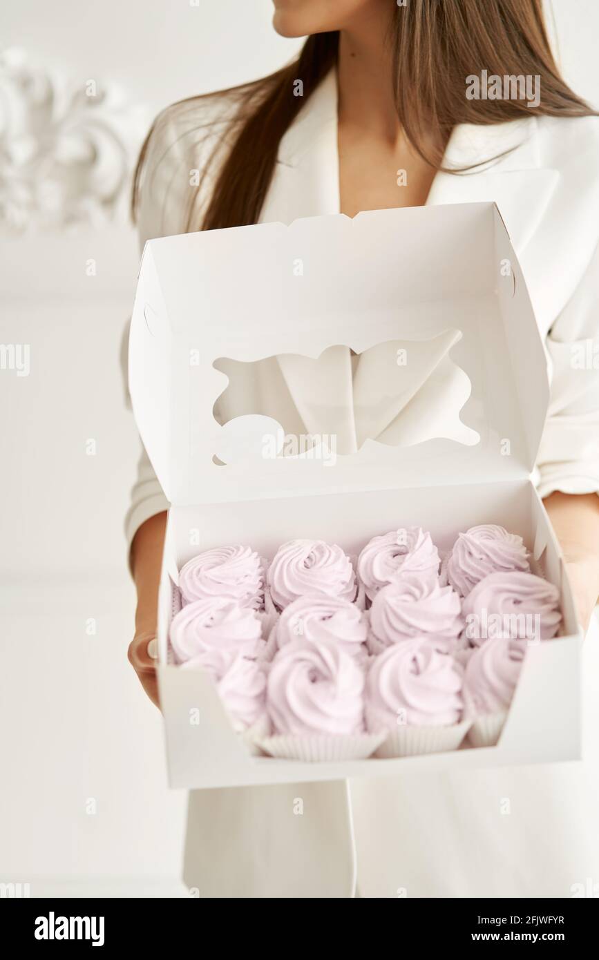 Chef pasticceria ragazza che tiene marshmallows rosa in confezione regalo Foto Stock