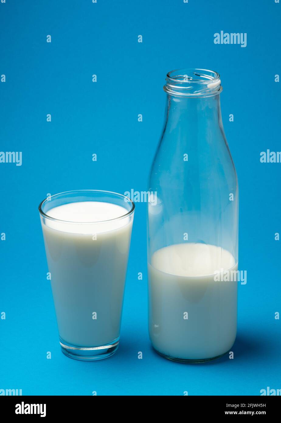 Bicchiere di latte fresco e bottiglia di latte isolato su fondo blu. Foto Stock