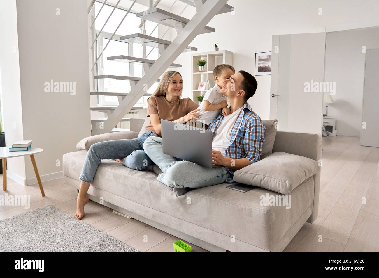Felici i genitori della famiglia ed il figlio carino del capretto che si diverte usando il laptop a casa. Foto Stock