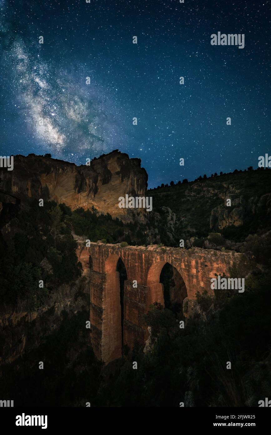 Cielo stellato paesaggio. Antico acquedotto romano conosciuto come 'Peña Cortada' e la Via Lattea vista in estate nell'Emisfero Nord. Valencia, Spagna Foto Stock