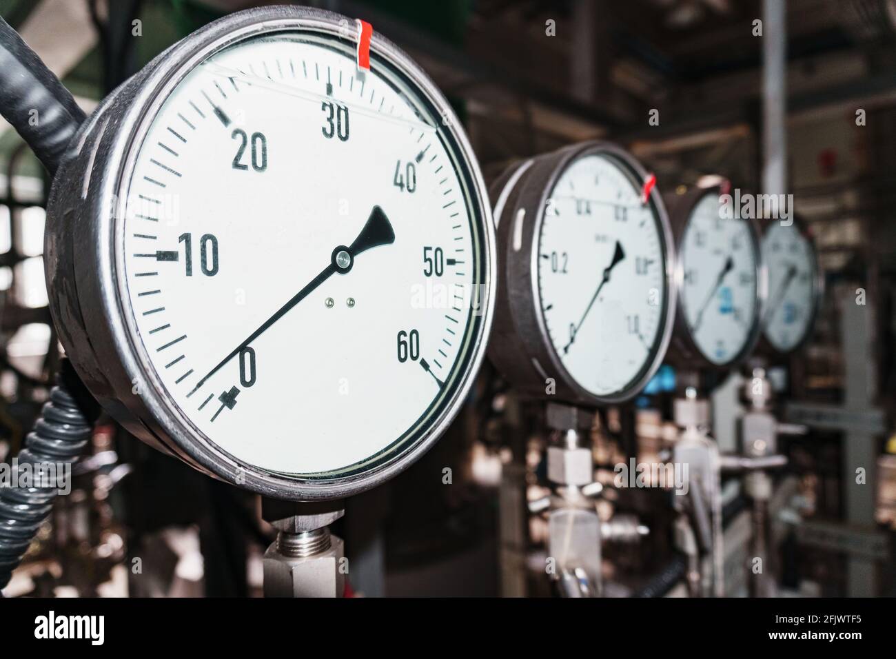 Il manometro è un dispositivo di misurazione della pressione di primo piano in fila. Misurazione della pressione di liquidi e gas negli impianti industriali Foto Stock