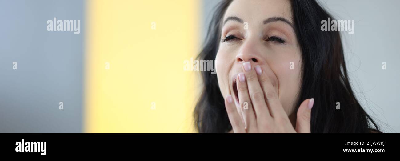 Ritratto di giovane donna di bruna yawning a casa Foto Stock