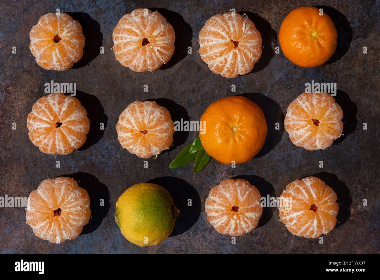 Diversi mandarini sbucciati e sbucciati si trovano accanto l'uno all'altro su una superficie marmorizzata Foto Stock