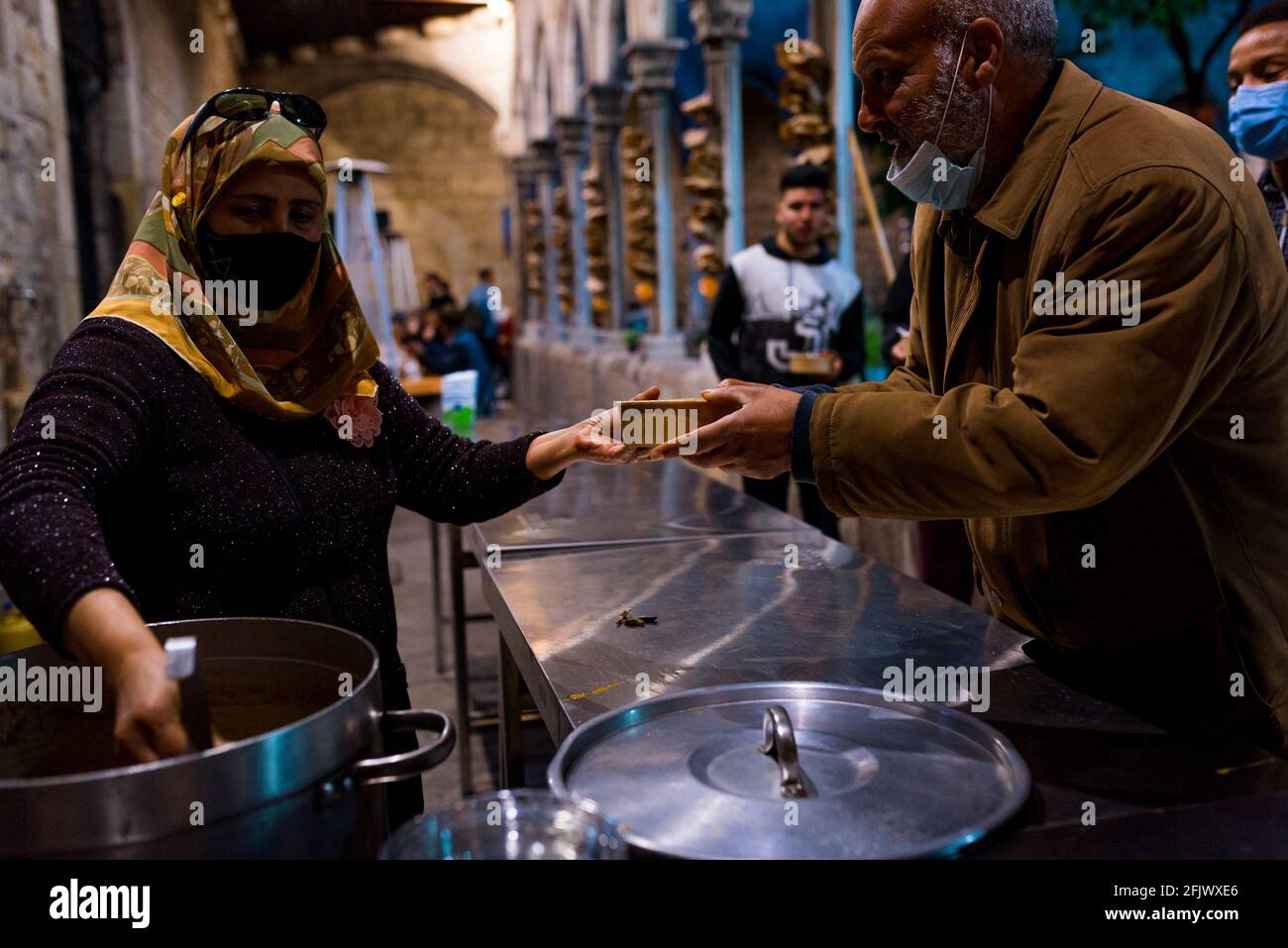 ESP. 23 Apr 2021. Un volontario serve gratuitamente piatti caldi di Iftar nella cucina di beneficenza durante il mese santo di digiuno musulmano del Ramadan nella chiesa di Sant'Anna a Barcellona, in Spagna, il 23 aprile 2021. La crisi economica provocata dalla pandemia significa che si è verificato un aumento della domanda di pasti gratuiti da parte dei settori più poveri e svantaggiati della società in Catalunya e Spagna (Foto di Davide Bonaldo/Sipa USA) Credit: Sipa USA/Alamy Live News Foto Stock