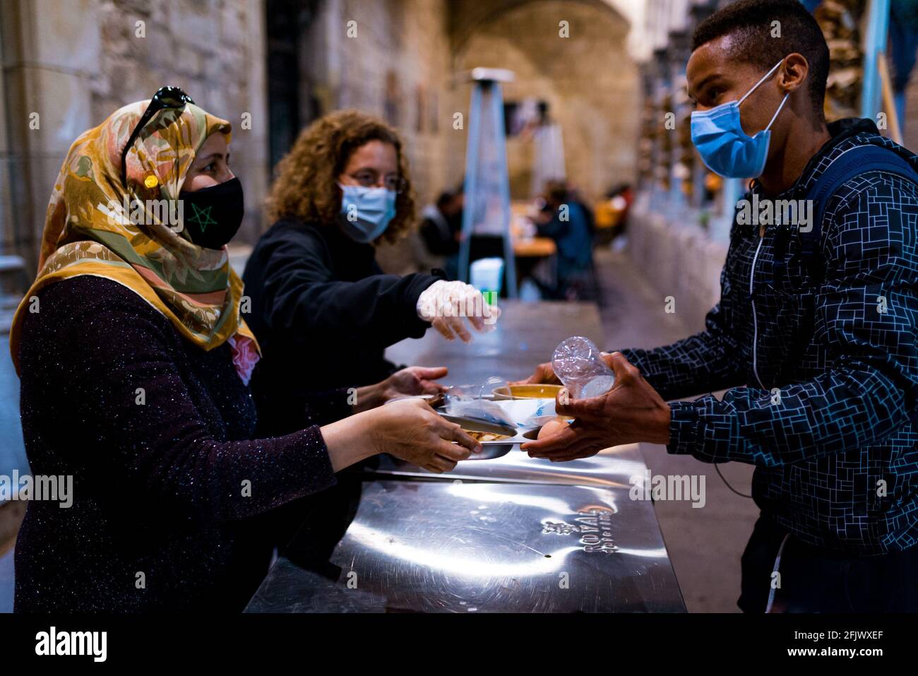 ESP. 23 Apr 2021. Un volontario serve gratuitamente piatti caldi di Iftar nella cucina di beneficenza durante il mese santo di digiuno musulmano del Ramadan nella chiesa di Sant'Anna a Barcellona, in Spagna, il 23 aprile 2021. La crisi economica provocata dalla pandemia significa che si è verificato un aumento della domanda di pasti gratuiti da parte dei settori più poveri e svantaggiati della società in Catalunya e Spagna (Foto di Davide Bonaldo/Sipa USA) Credit: Sipa USA/Alamy Live News Foto Stock