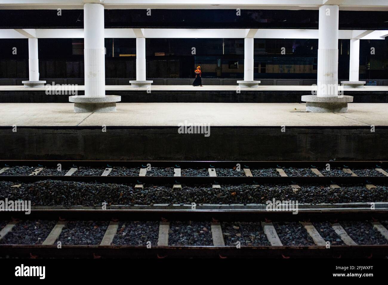 Una donna trasportava il suo bambino e attraversava l'incrocio ferroviario nella stazione ferroviaria di Khulna in Bangladesh. Foto Stock