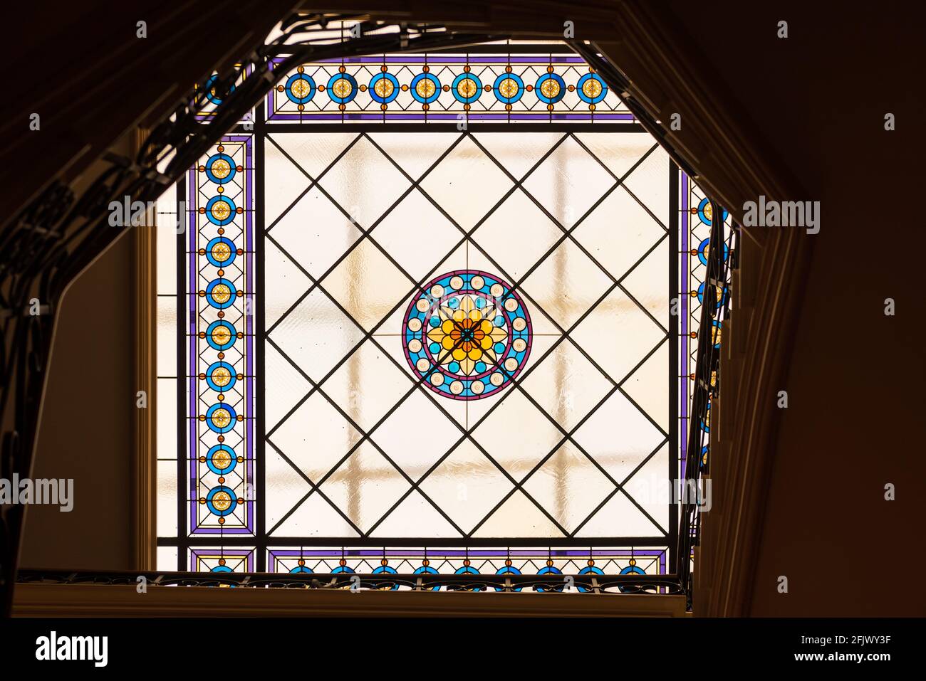 Una colorata finestra di vetro colorato posta sul soffitto, composta da piastrelle di vetro rotonde e quadrate che illuminano l'interno delle scale. Foto Stock