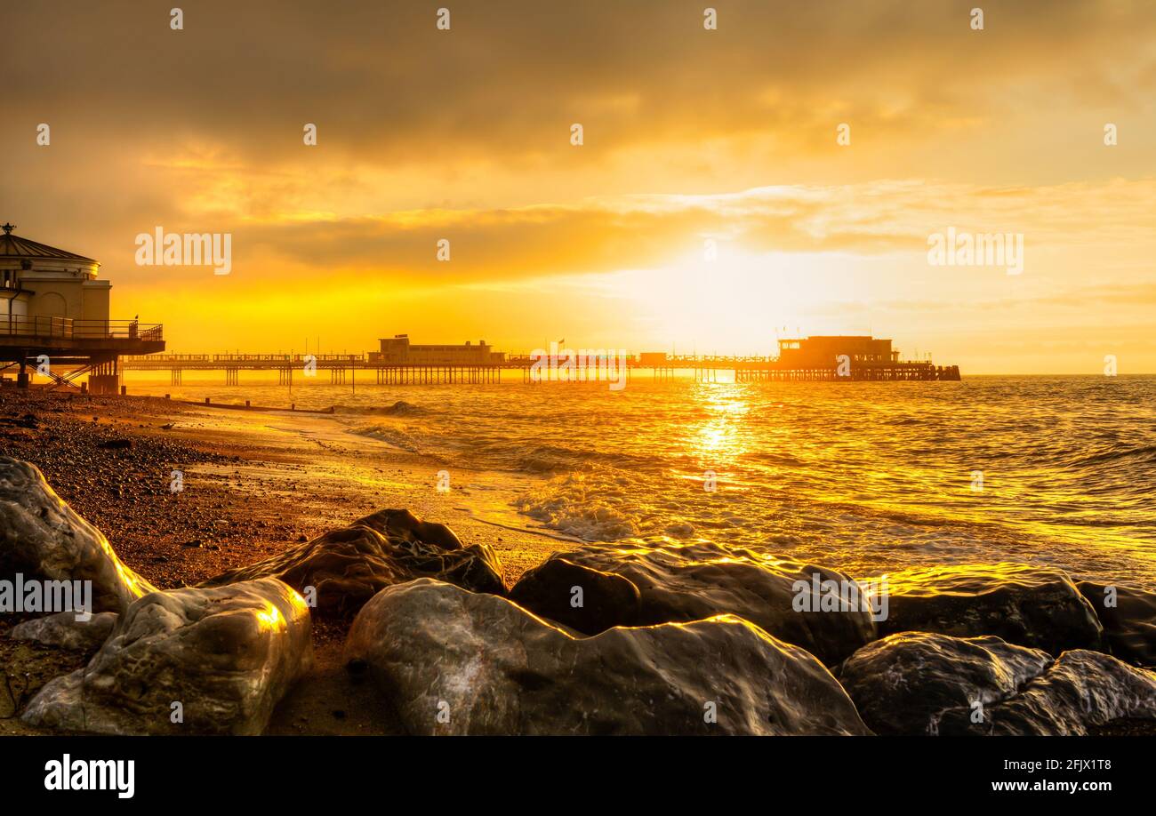 Il sorgere del sole oltre il molo e il mare in autunno a Worthing West Sussex, in Inghilterra, Regno Unito. Foto Stock