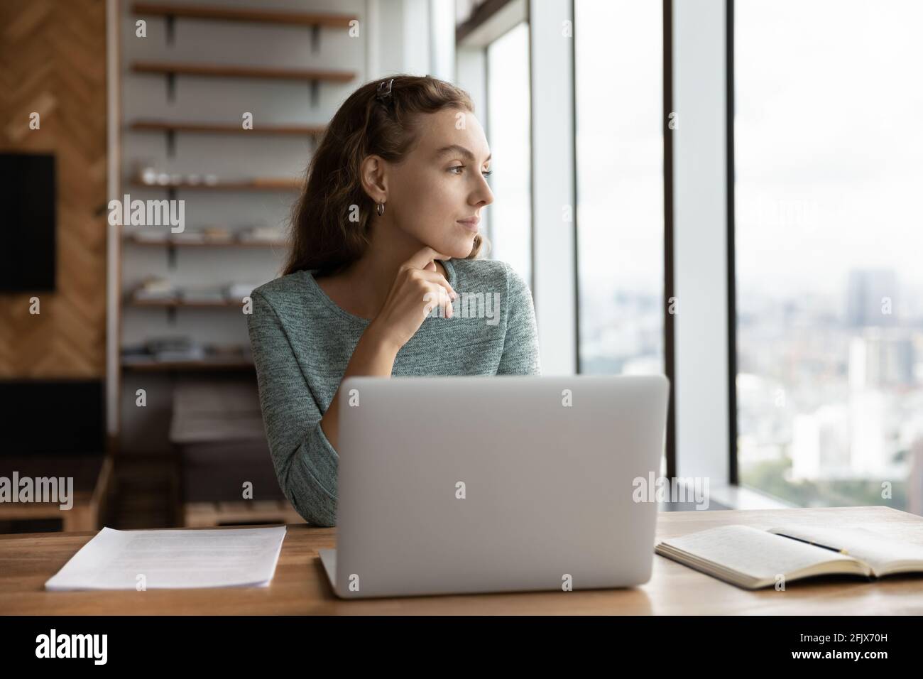 La pensiva dipendente femminile lavora sul pensiero dei notebook Foto Stock