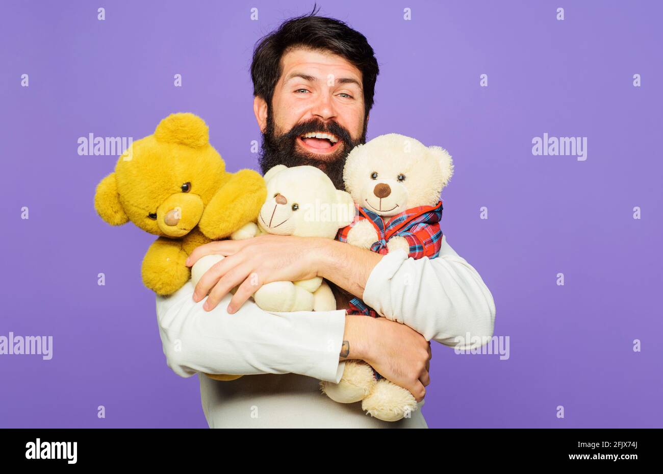 Sorridente uomo bearded abbracci Teddy Bears. Uomo felice con peluche. Regalo e regalo. Foto Stock
