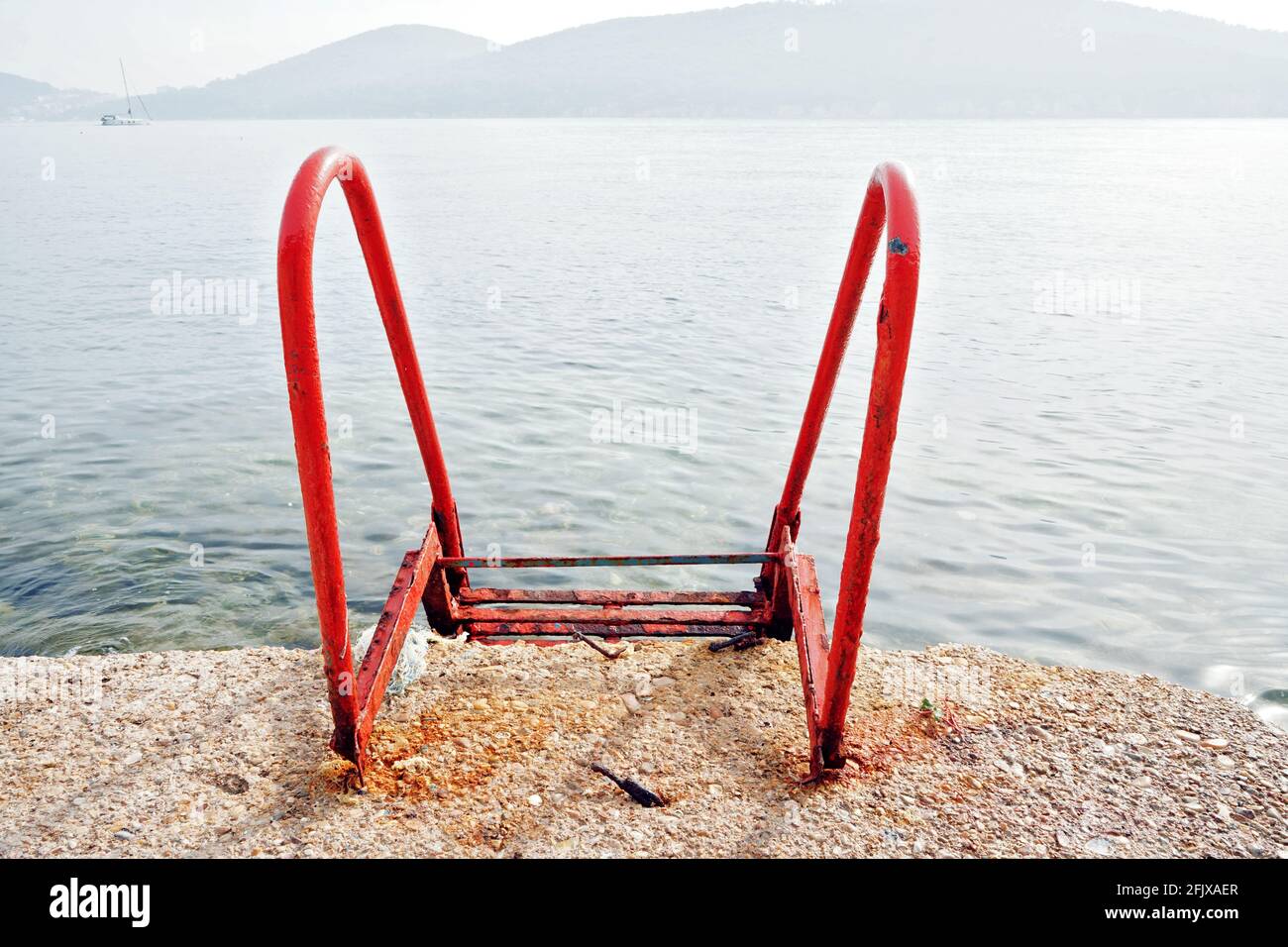 Scala rossa per nuotare in mare con bacineria di nebbia. Foto Stock