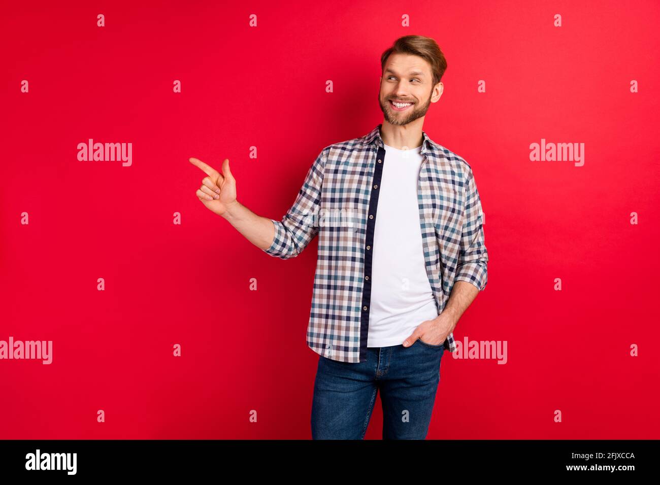 Foto di giovane uomo felice positivo sorriso guardare dito punto spazio vuoto consiglia consigli ad isolato su sfondo rosso Foto Stock