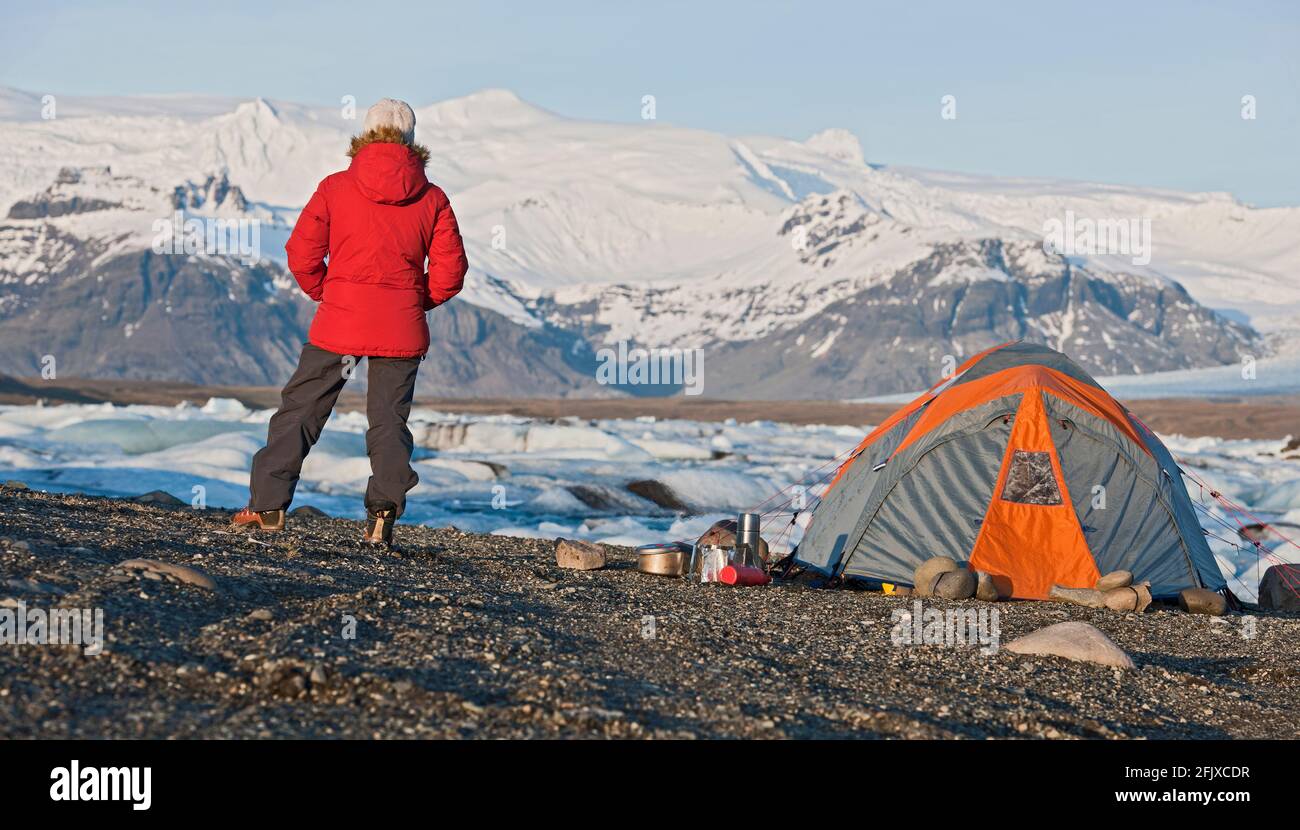 Donna in piedi al campo presso la famosa laguna glaciale JÃ¶kulsÃ¡rlÃ³n Foto Stock