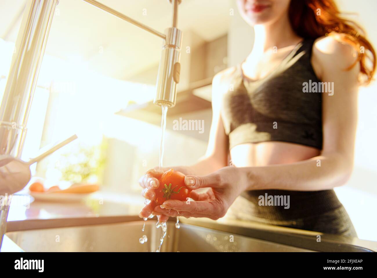 Fitness woman risciacqua il pomodoro fresco nel lavandino Foto Stock