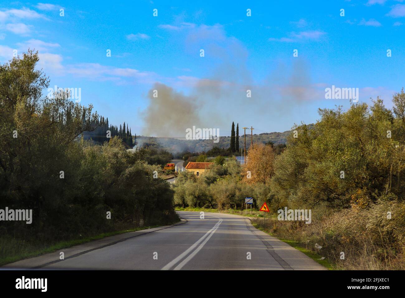 Guida attraverso la penisola del Peloponneso nel tardo pomeriggio durante l'ulivo vendemmiate con il fumo degli incendi di olive in lontananza a nord di Kalamati Greec Foto Stock