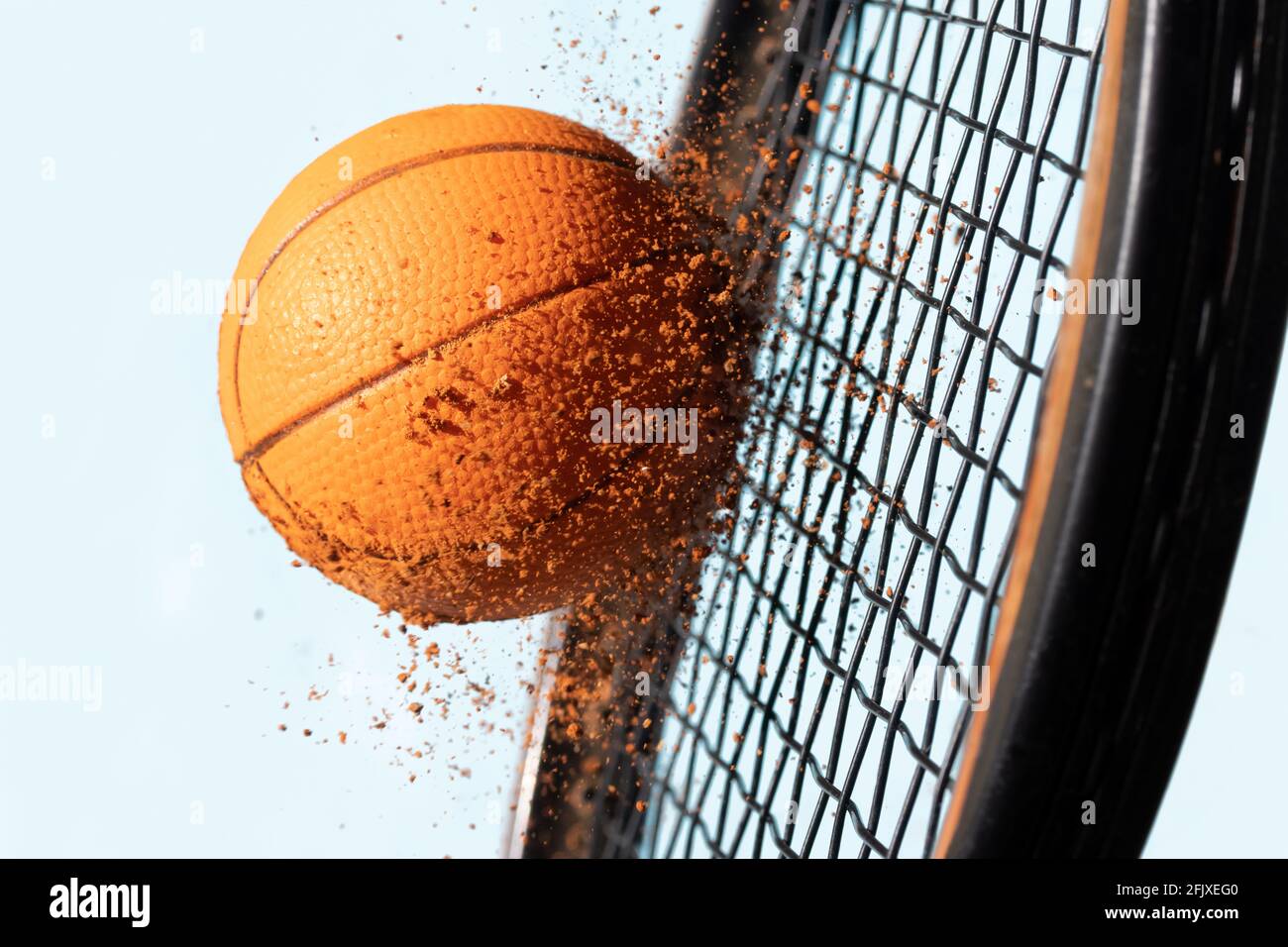 Un colpo con una racchetta da tennis ad una palla sporca con argilla rossa che vola intorno, uno sfondo di cielo blu, vista ravvicinata Foto Stock