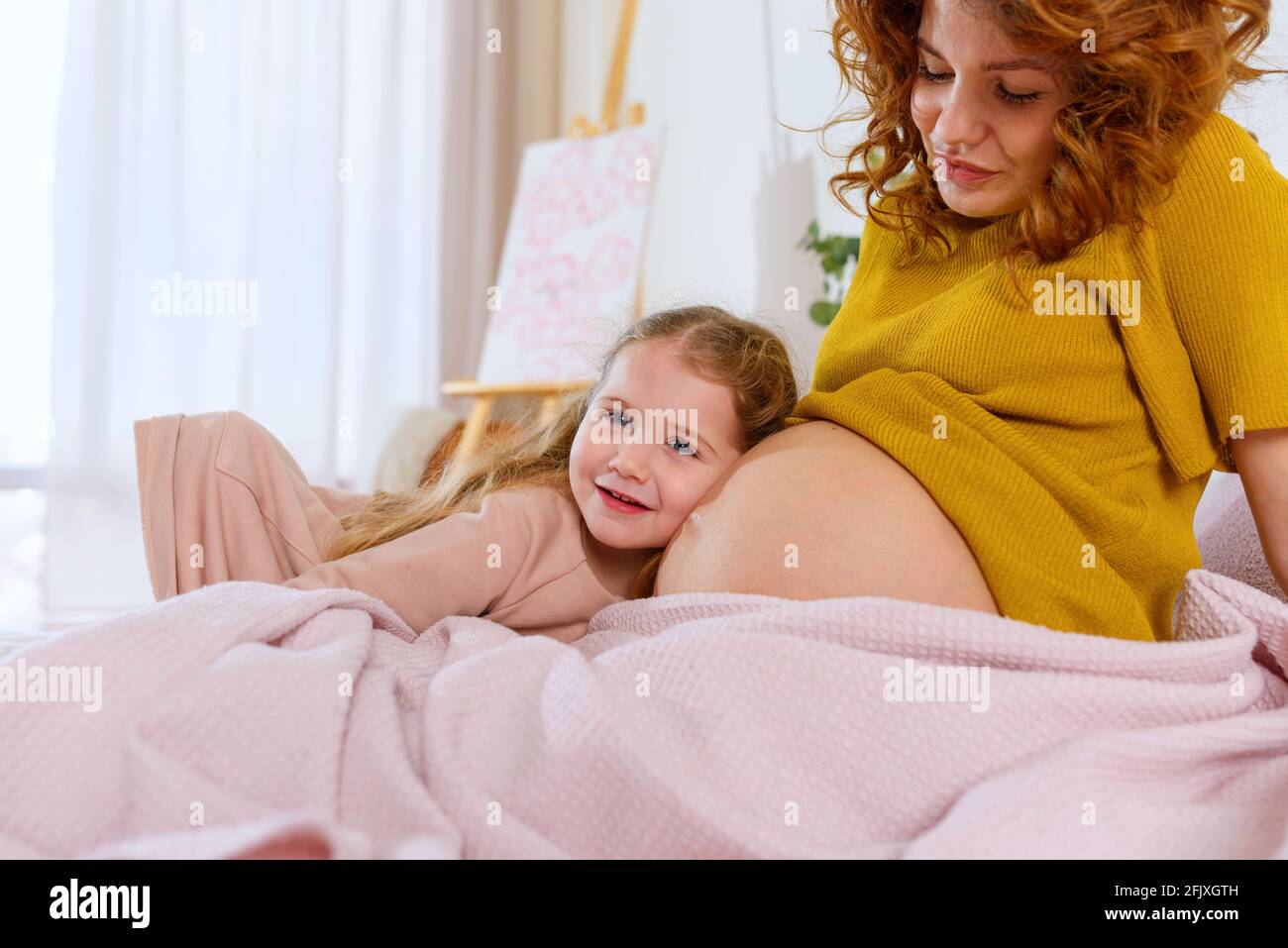 Mamma incinta gioca con sua figlia. Concetto di famiglia, gioia e gravidanza Foto Stock