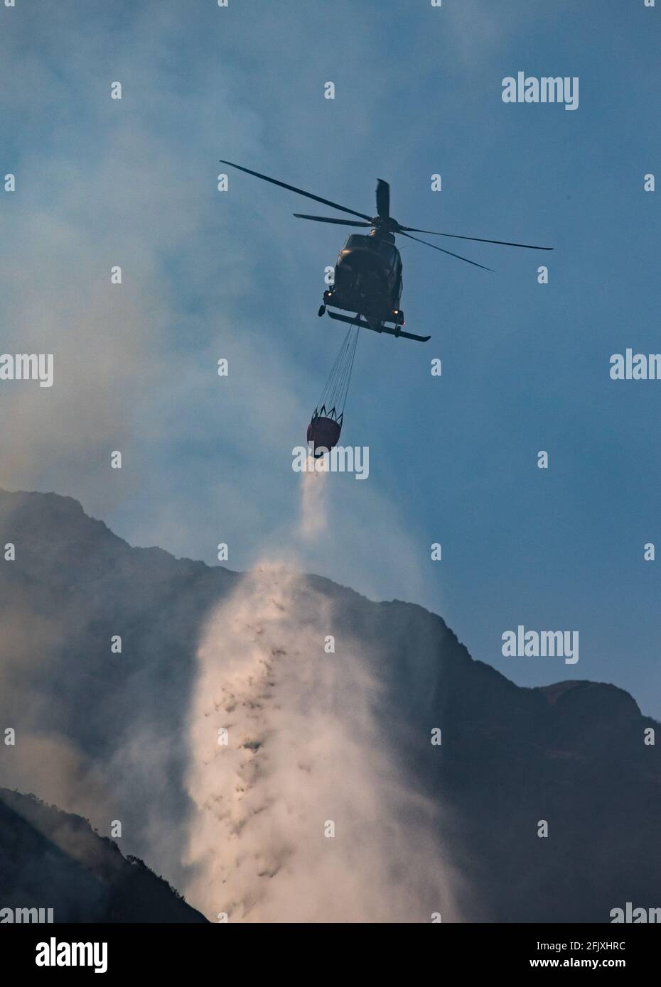 Killarney National Park, Irlanda - 26 aprile. 2021: L'elicottero Irish Air Corp scarica l'acqua per spegnere il fuoco nel parco nazionale di Killarney. Foto Stock