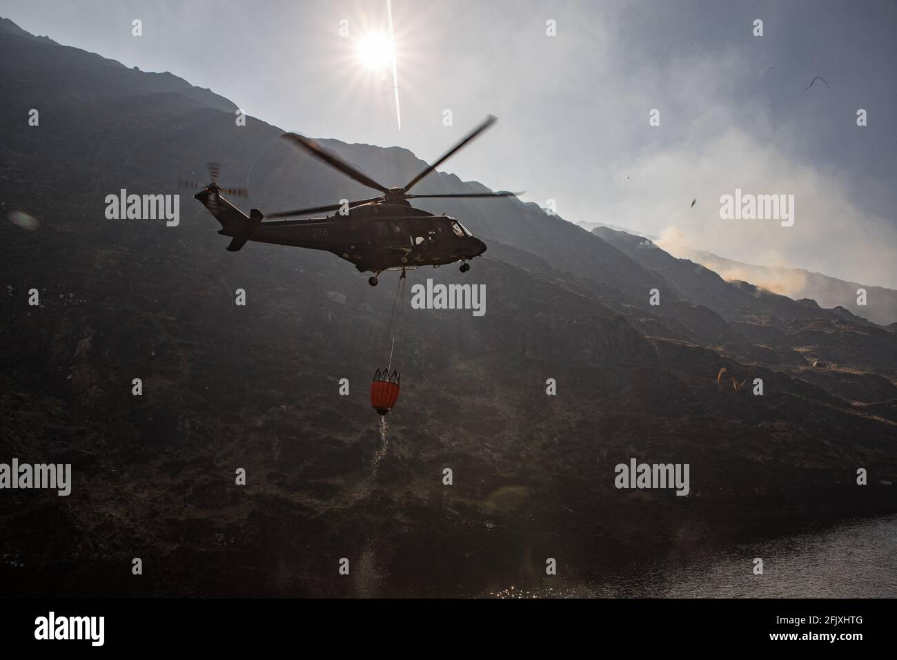 Killarney National Park, Irlanda - 26 aprile. 2021: Elicottero Irish Air Corp che raccoglie acqua per spegnere il fuoco nel parco nazionale di Killarney Foto Stock