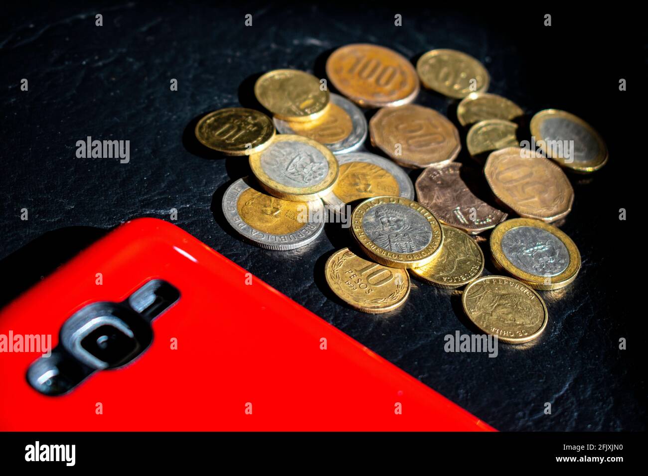 Contanti: Monete cilene di peso e telefono cellulare. Foto Stock