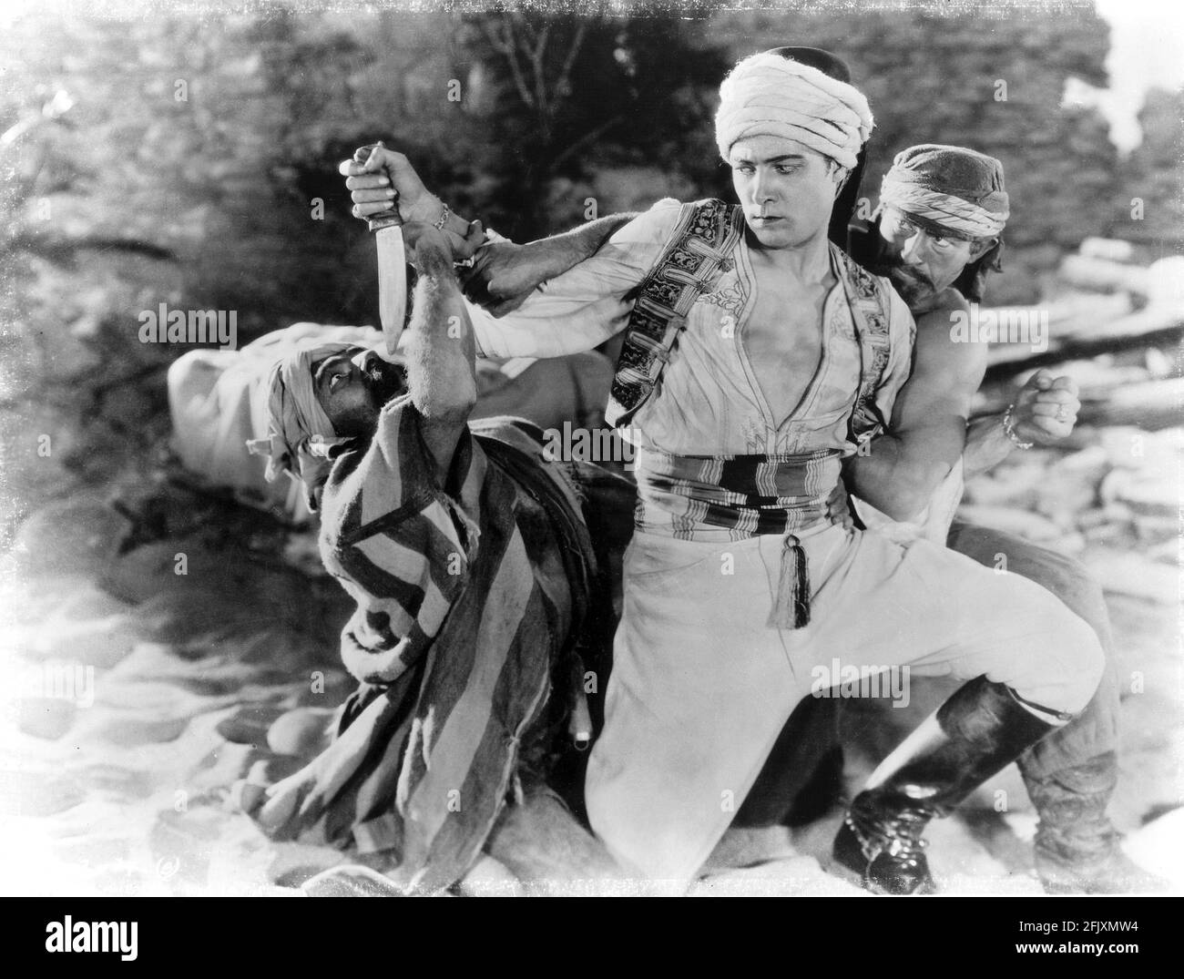 1926 , USA : l'attore di film muto RUDOLPH VALENTINO (1895 - 1926 ) con il toro Montana IN FIGLIO DELLO SCEICCO ( il figlio dello Sceicco ) di George Fitzmaurice , tratto dal romanzo di Edith Maude Hull , Paramount Picture - CINEMA MUTO - RODOLFO VALENTINO - studio cinematografico - lotta - wrestling - LATIN LOVER - italoamericano - italo americano - italo-americano - emigrante - emigrante - italo-americano - ritratto - ritratto - turbante - turbante - turbante - coltello - pugnale - stivali - arabo - arabo ---- Archivio GBB Foto Stock