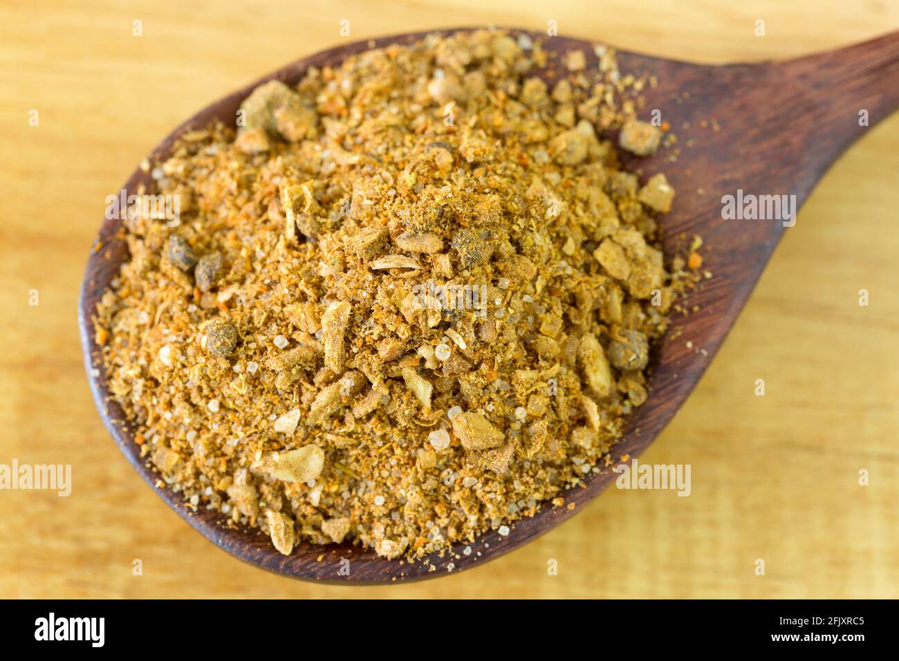 Bistecca di primo piano condimento marinata in polvere piena di spezie grossolanamente macinate in cucchiaio di legno su fondo di legno Foto Stock