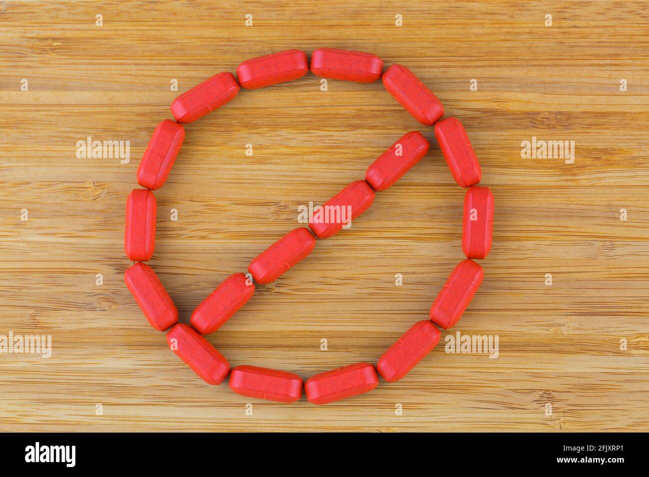 Le vitamine multiple rosse si organizzano nel segno di arresto. Compresse rivestite con film di minerali, formula anti stress su legno, sfondo Foto Stock