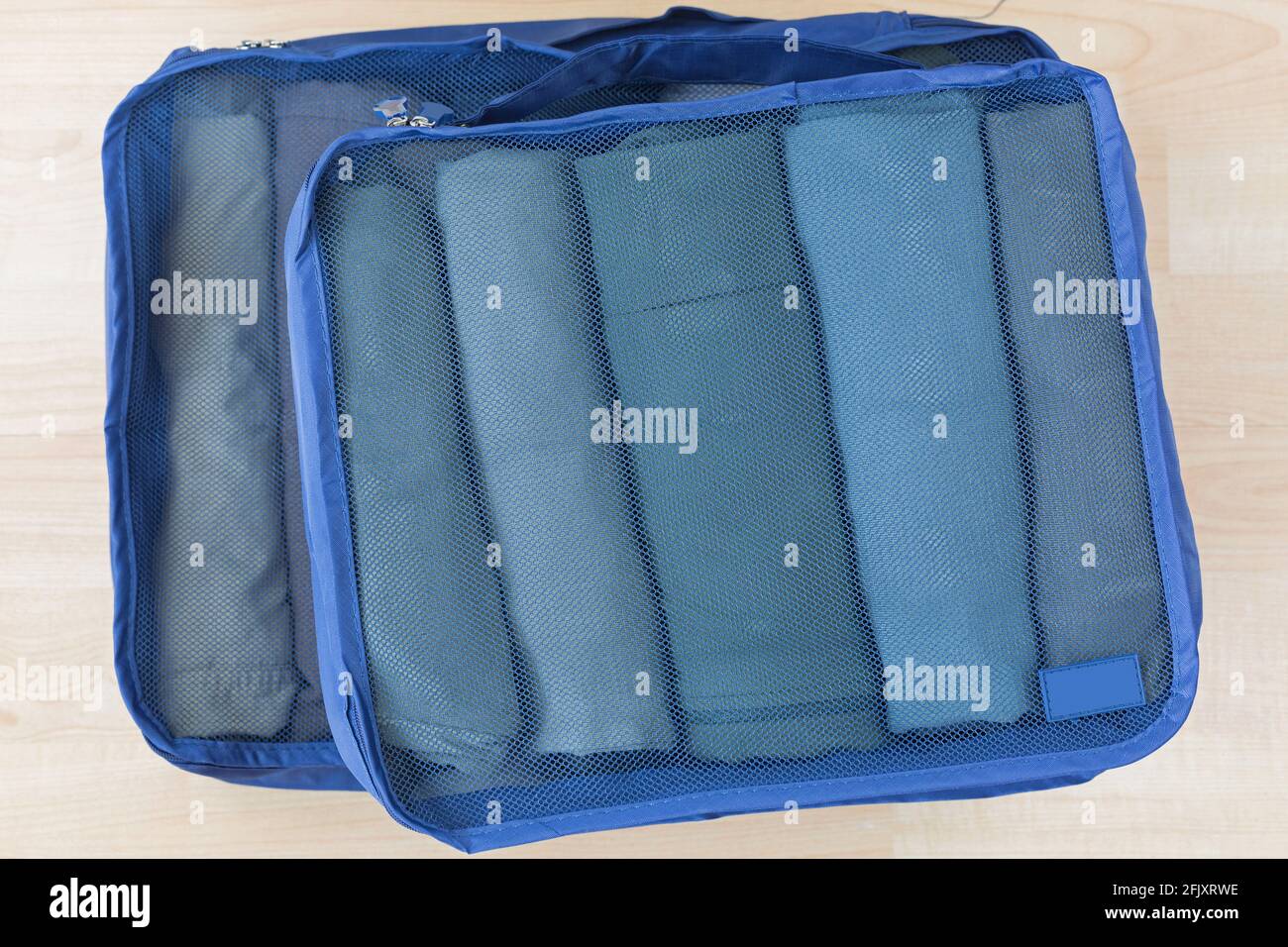 Borse a maglia cubica con vestiti arrotolati, t-shirt, pantaloni. Set di organizer di viaggio per aiutare a imballare i bagagli facile e ben organizzato Foto Stock