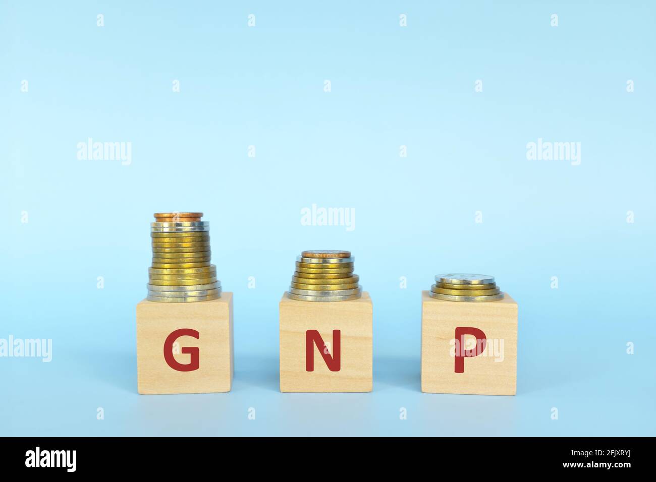 Le lettere del prodotto nazionale lordo o del prodotto nazionale lordo in blocchi di legno con una pila decrescente di monete. Crisi economica, declino e concetto di recessione. Foto Stock