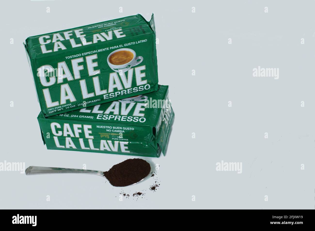 Caffè cubano la Llave in scatole e un cucchiaio pieno di caffè in polvere su sfondo bianco con copia spazio Foto Stock