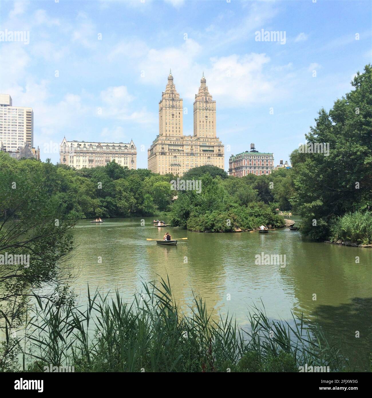 Vista sul lago nel Central Park di fronte all'edificio San Remo. La gente sta cavalcando gondole e canoa. Foto Stock