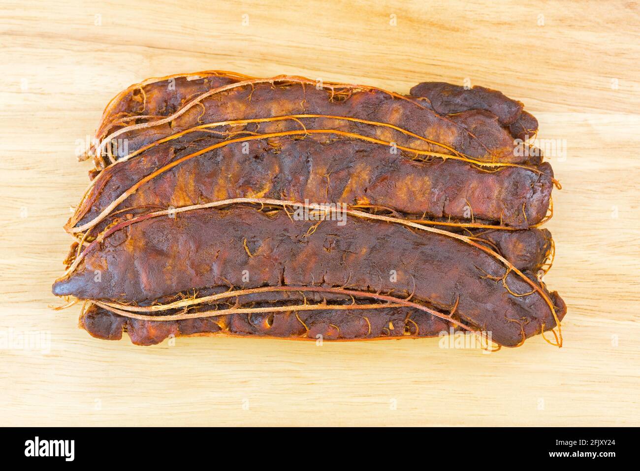 Vista dall'alto del Tamarind fresco acaro con guscio marrone rimosso per preparare la zuppa acida asiatica, su sfondo di legno (Tamarindus indica) Foto Stock