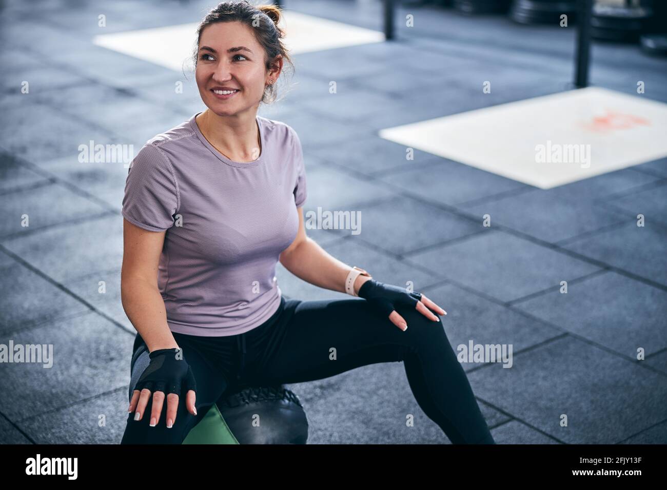 Sportiva ad alta velocità con guanti da allenamento senza dita che si guardano lontano Foto Stock
