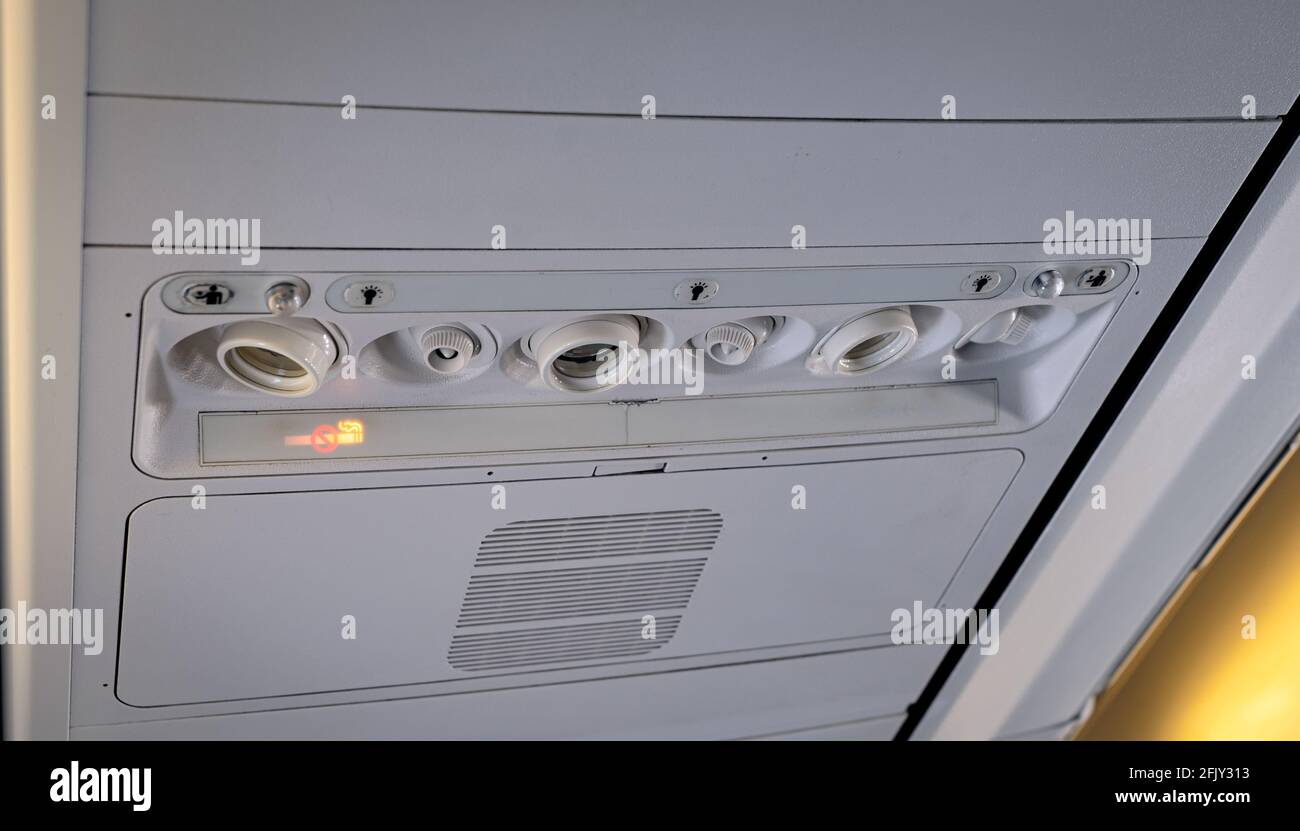 Pannello di controllo con aria condizionata, luce di lettura e pulsante di chiamata nel compartimento superiore di un aeromobile commerciale. Cartello per non fumatori illuminato. Foto Stock