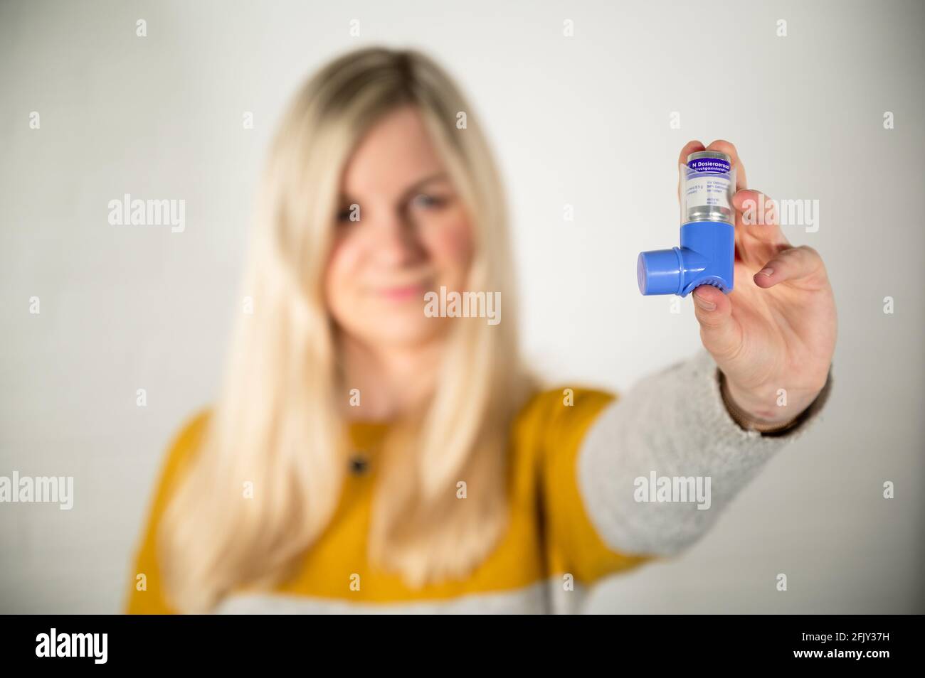 Giovane donna bionda che tiene un inalatore di spray di asma in lei mano Foto Stock